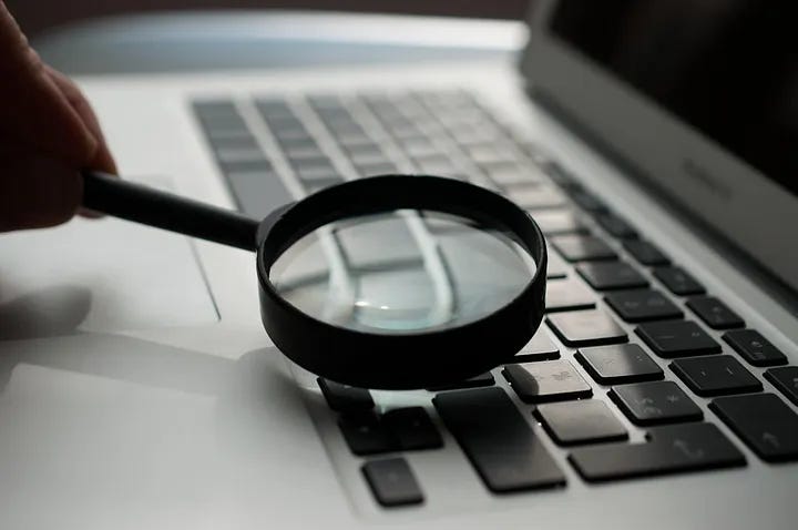 Photo of a magnifying class on a computer key board. Photo by Agence Olloweb on Unsplash