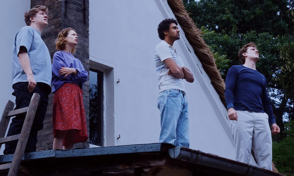 Four people stand on a roof looking off to the right. Four people stand on a roof looking off to the right.