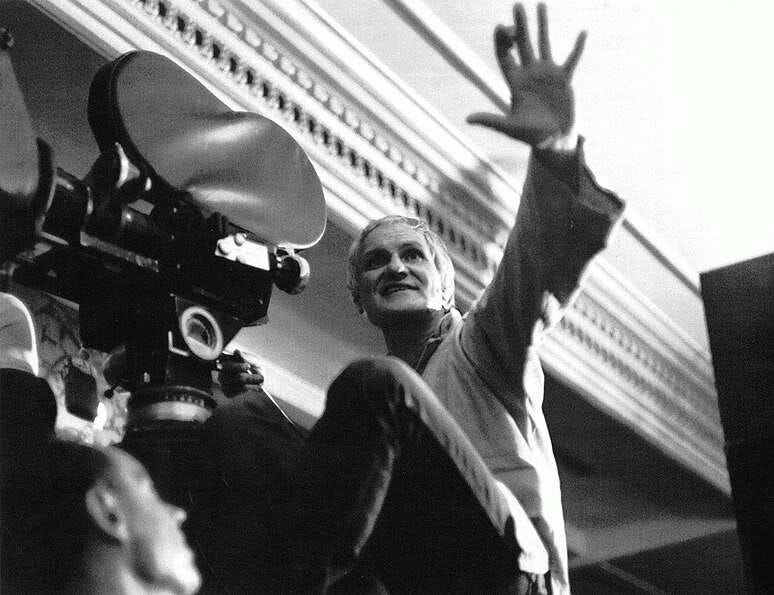 A black and white photo of Miklos Jancso operating a camera on a film set