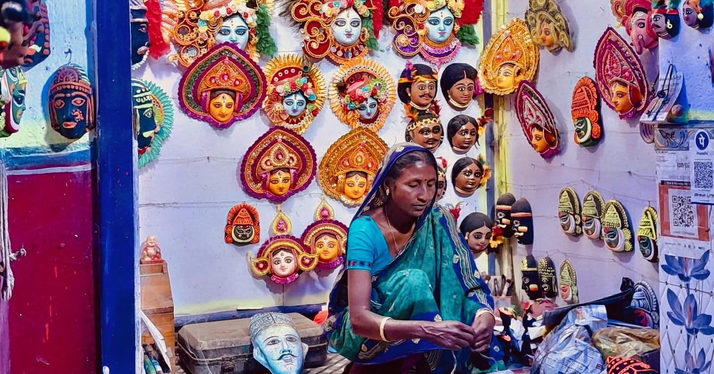 A woman packs a mask in her shop with walls covered with traditional Purulia Chhau masks. A woman packs a mask in her shop with walls covered with traditional Purulia Chhau masks.
