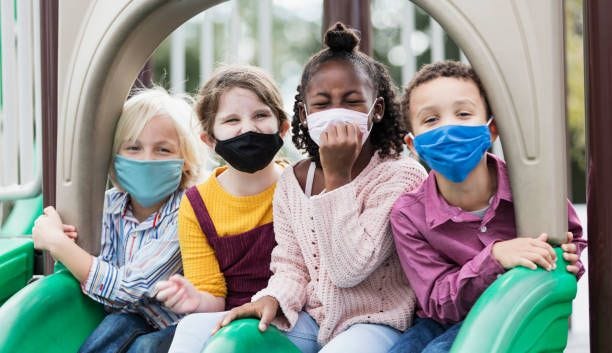 children on playground wearing face masks, covid-19 - protective face mask stock pictures, royalty-free photos & images
