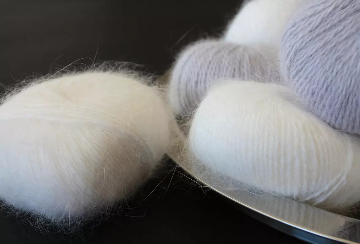 A mix of grey and cream Angora rabbit yarn on a silver tray. 
