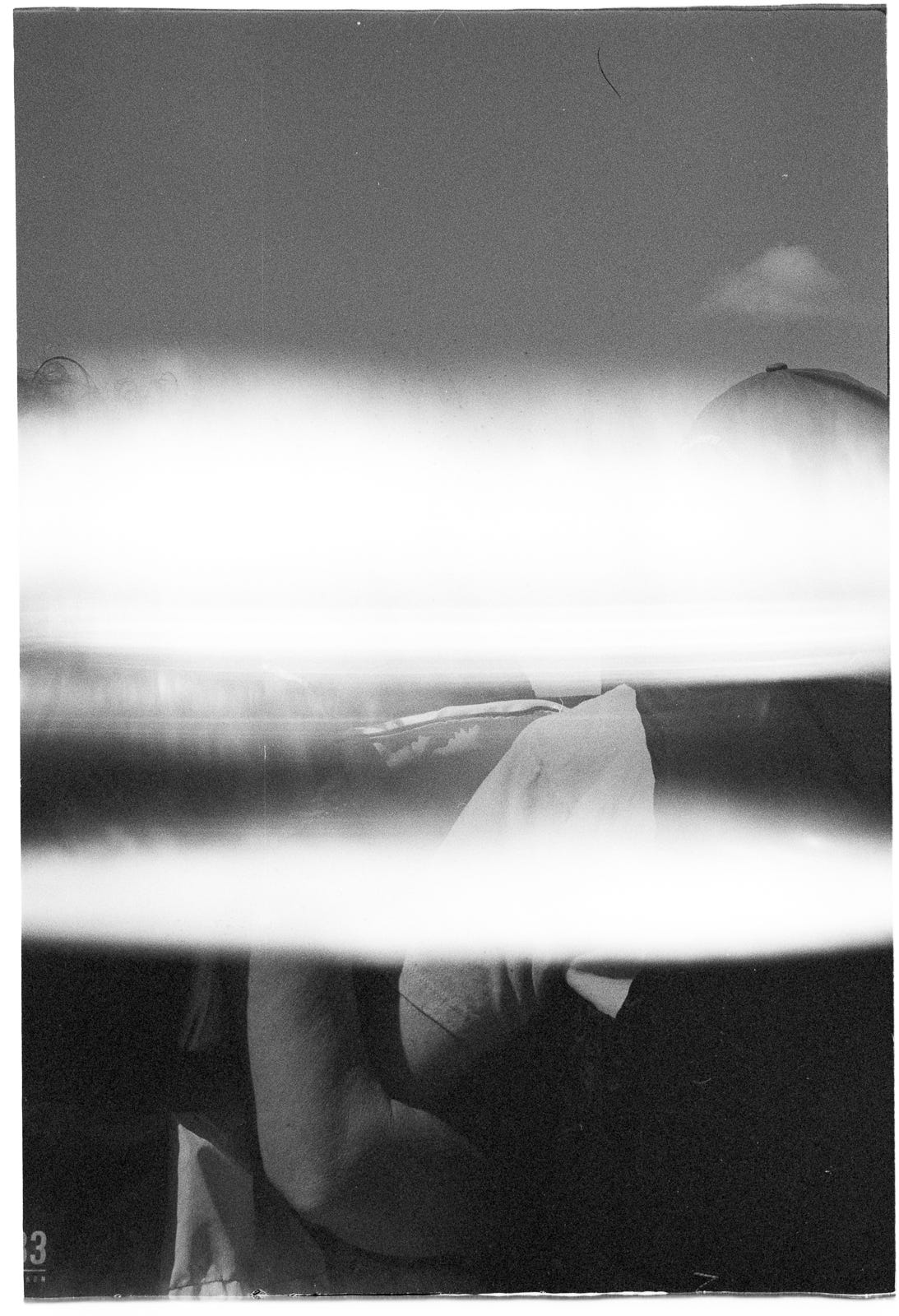 More light leak than image, a black and white analog image of two adults and a child sitting in a boat. More light leak than image, a black and white analog image of two adults and a child sitting in a boat.