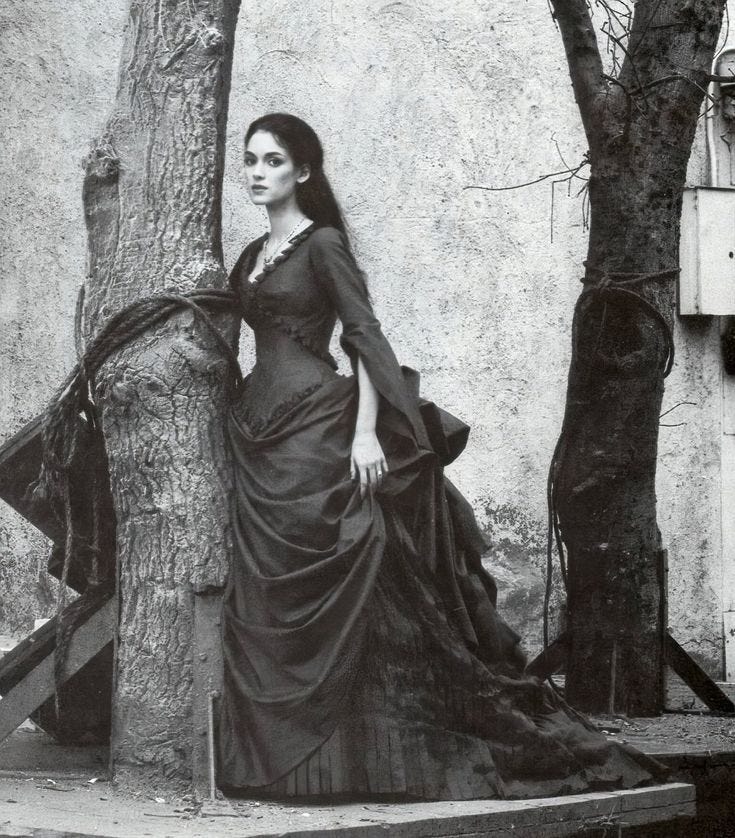 This may contain: an old black and white photo of a woman in a dress leaning against a tree This may contain: an old black and white photo of a woman in a dress leaning against a tree