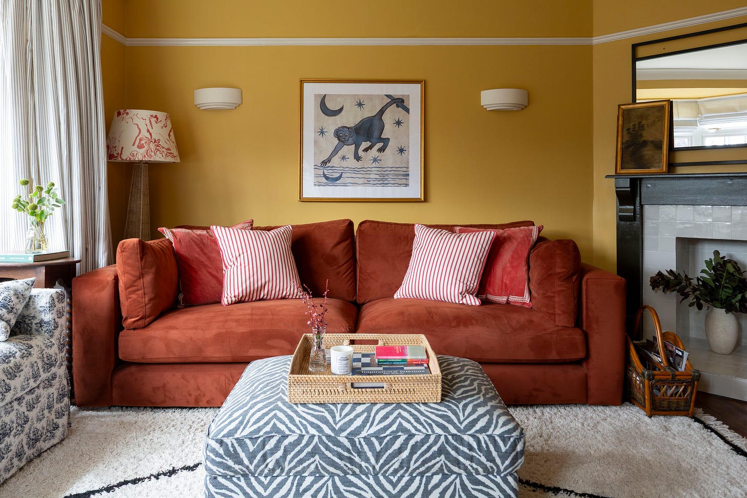 yellow living room with red sofa, zebra ottoman, cream rug