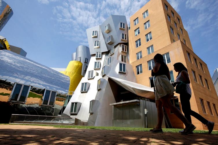 Young people walk past a modern building. Young people walk past a modern building.