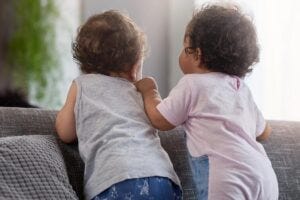 two babies standing on a couch