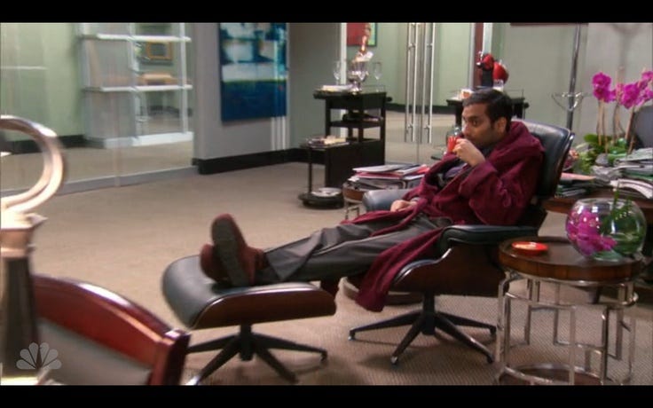 Office worker lounging in a robe with feet up, sipping tea in Parks and Recreation scene, symbolizing a disengaged employee. Office worker lounging in a robe with feet up, sipping tea in Parks and Recreation scene, symbolizing a disengaged employee.