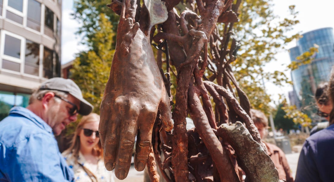 A close-up of a bronze hand with a crowd of people around it A close-up of a bronze hand with a crowd of people around it