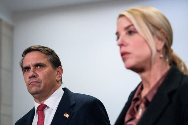 Todd Blanche with Pam Bondi. He’s wearing a dark suit with a red tie and an American flag pin. Todd Blanche with Pam Bondi. He’s wearing a dark suit with a red tie and an American flag pin.