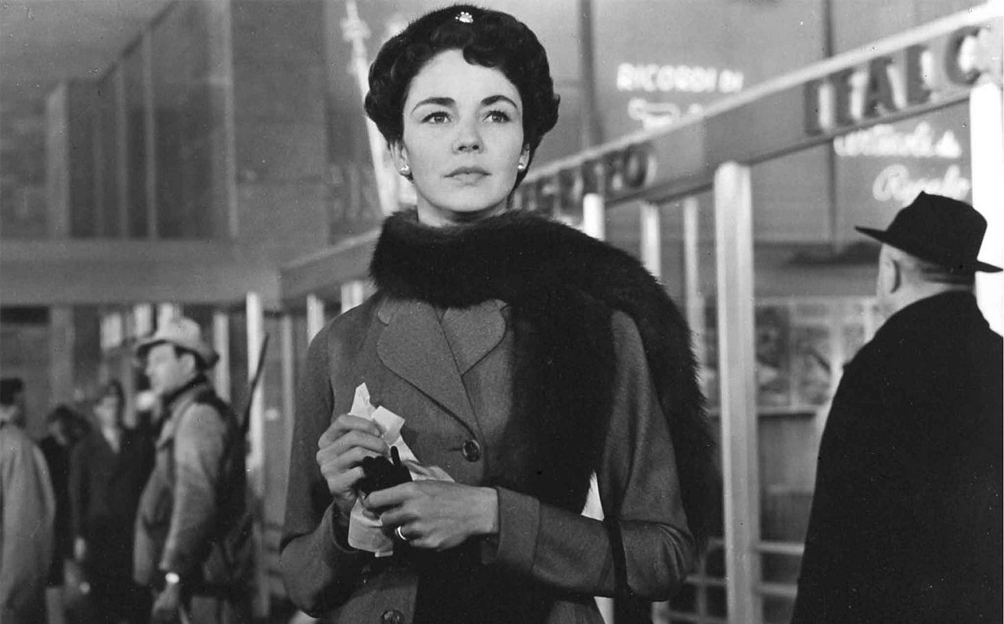 Jennifer Jones standing in a railway concourse, crowds milling around her Jennifer Jones standing in a railway concourse, crowds milling around her