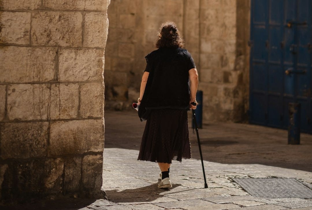 woman in black jacket walking on sidewalk during daytime