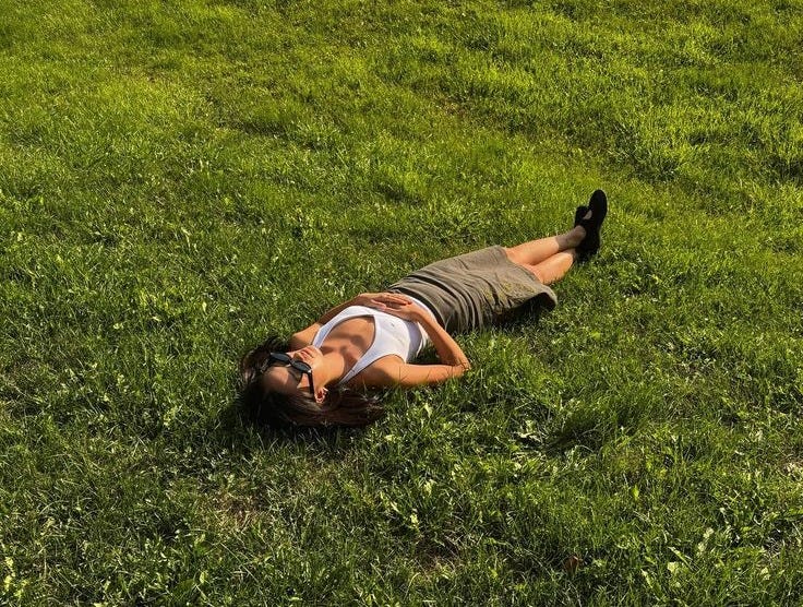 This may contain: a woman laying in the grass on her stomach