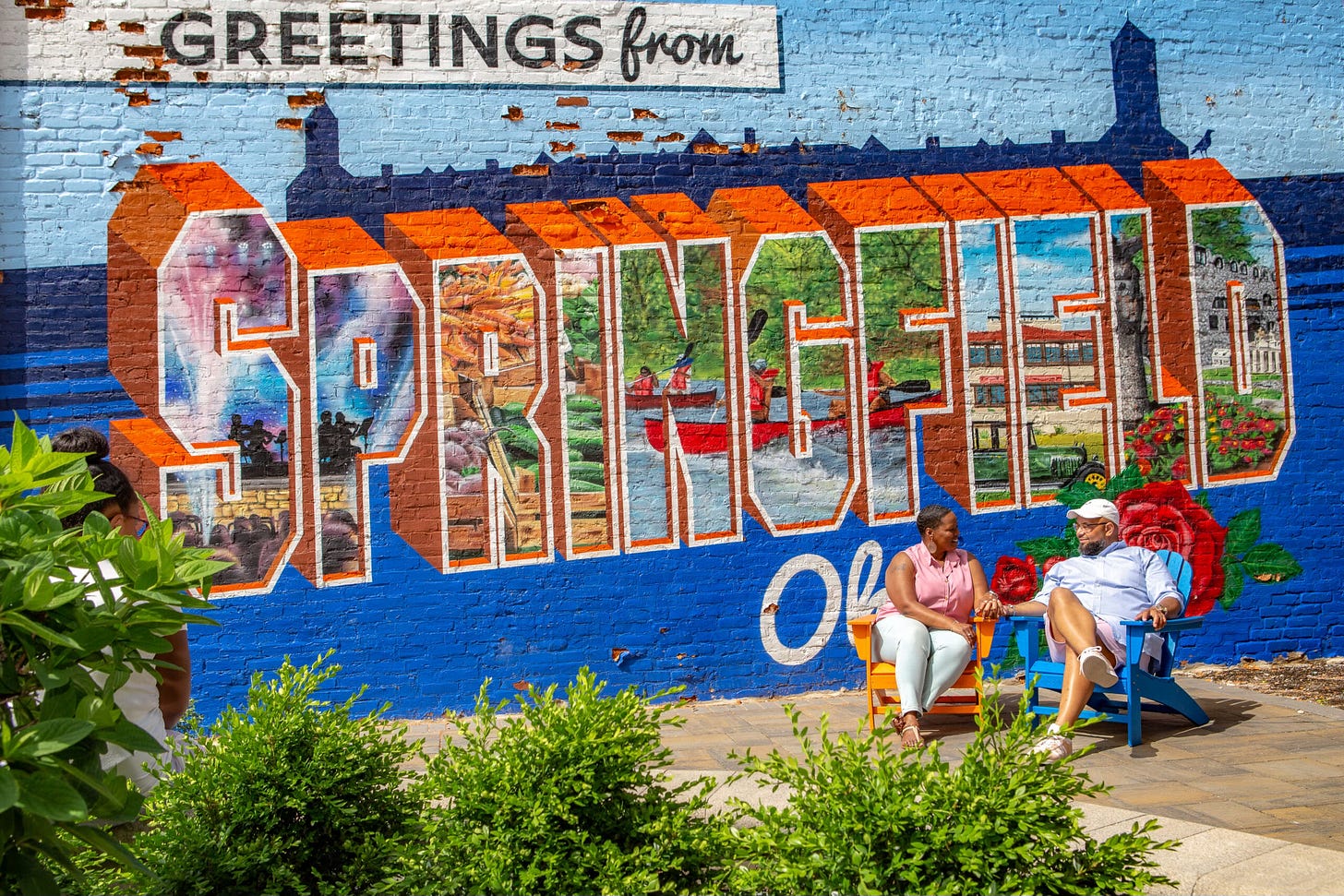 couple sitting on chairs in front of Welcome to Springfield Ohio mural