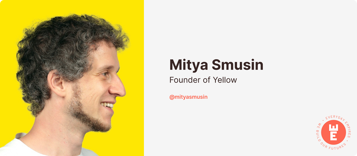 Photo of Mitya smiling and looking to the viewer's right. He's standing in front of a bright yellow background.