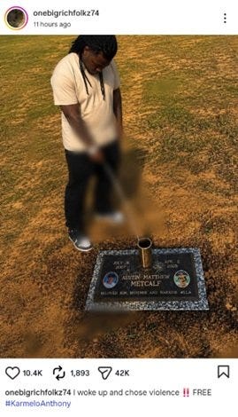 Person standing by a gravestone for Austin Matthew Metcalf, with flowers and a candle placed on the memorial.