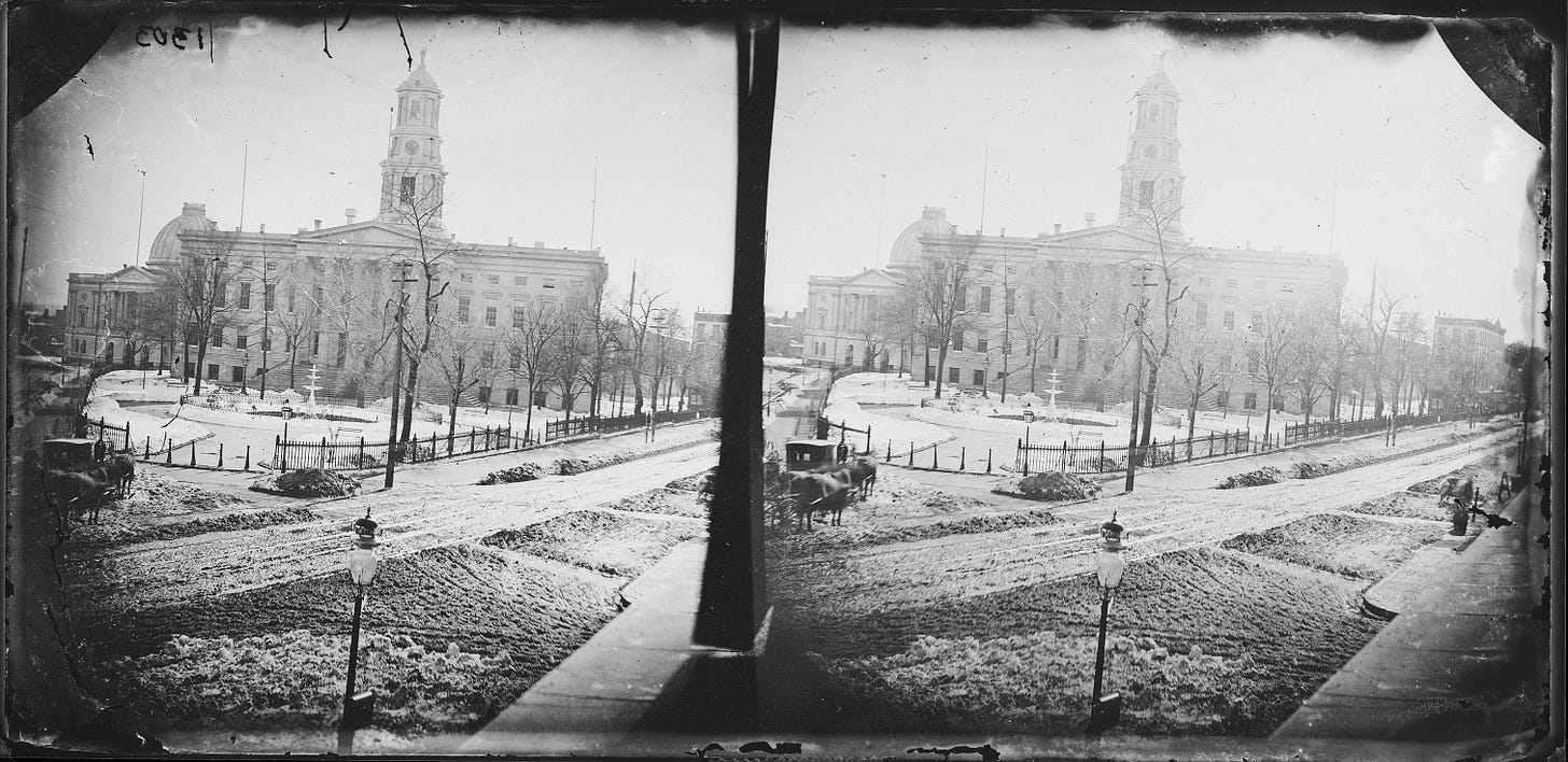 black and white image showing city hall and a park in front with a fountain