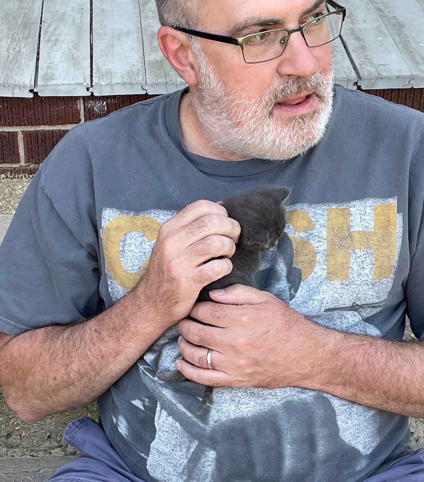 Brian holding a tiny kitten to his chest.