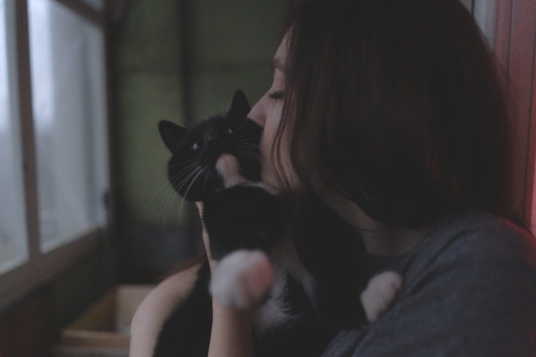 a woman holding a black and white cat in her arms