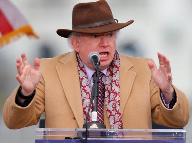 A person in a suit and hat is holding a microphone at a podium, likely giving a speech.

AI-generated content may be incorrect.