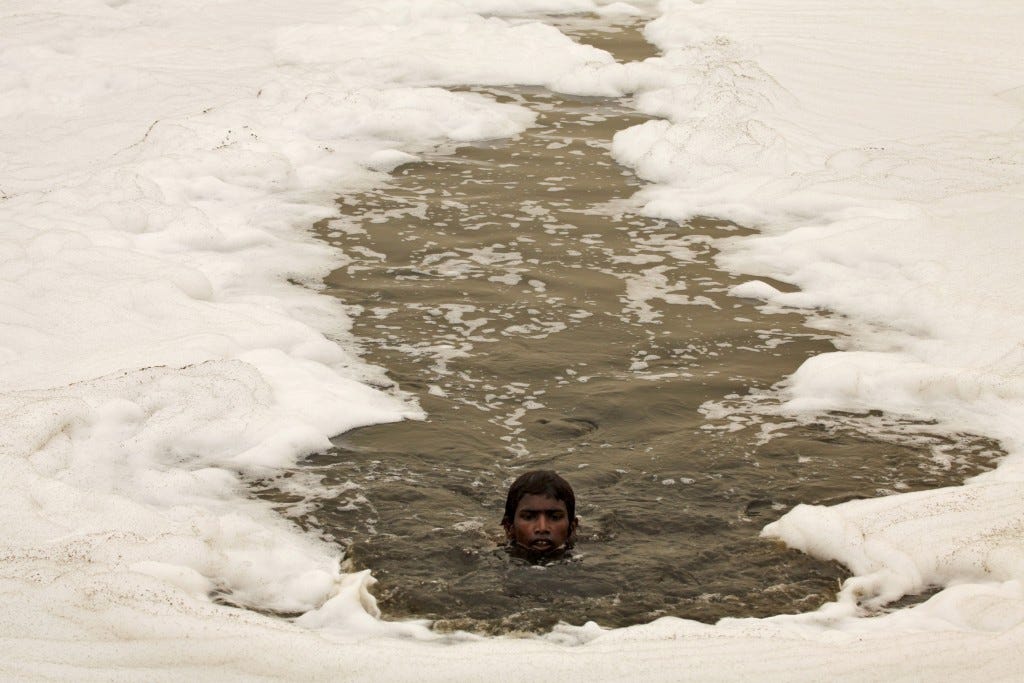 A boy swims in the polluted water of the Yamuna River to dive for offerings thrown in by worshippers amidst a dust haze in New Delhi during World Environment Day in 2010. Photo by Reinhard Krause/Reuters