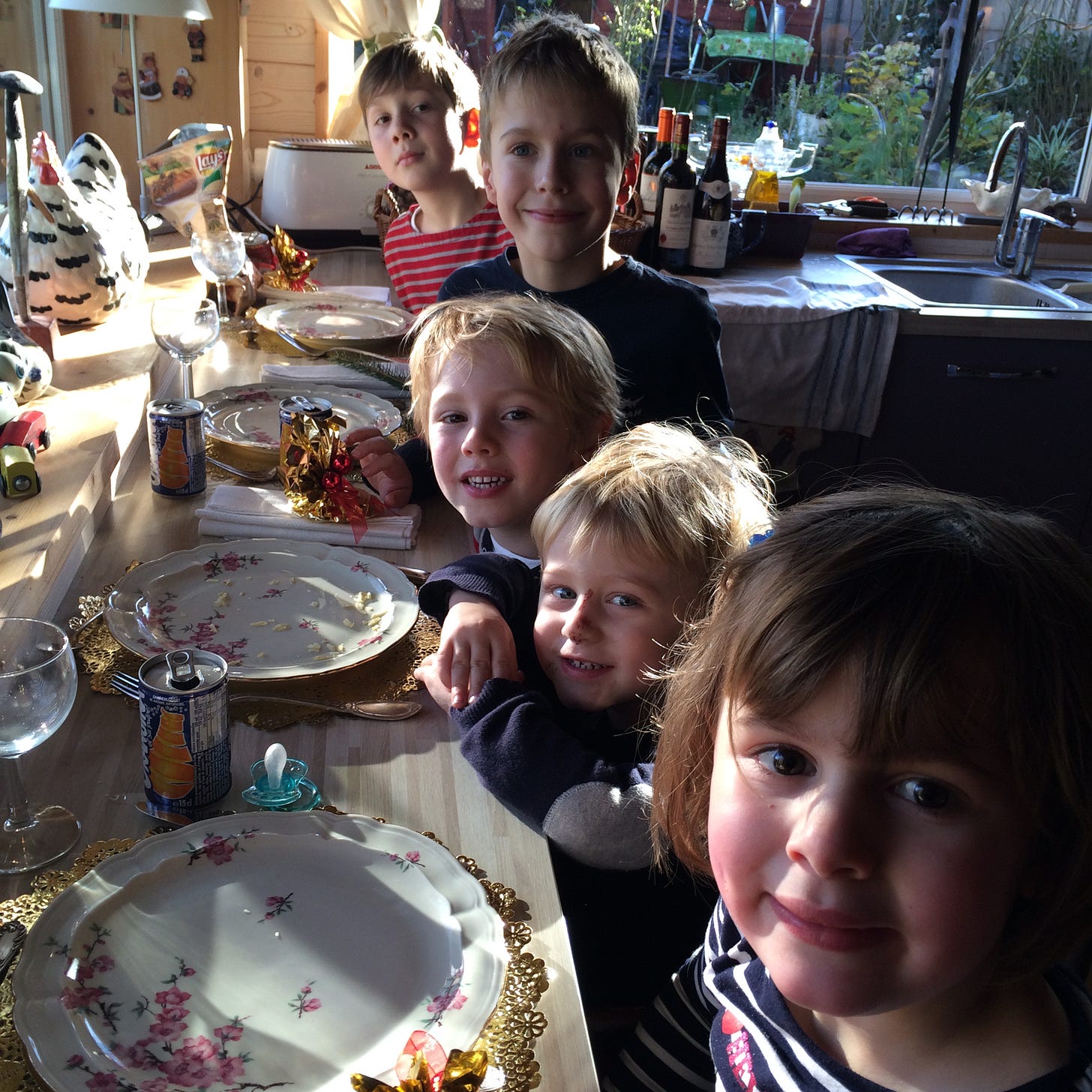 Young French children excitedly wait at a kitchen counter for dinner to arrive.
