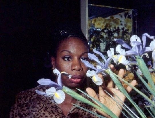 This may contain: a woman holding flowers in front of her face