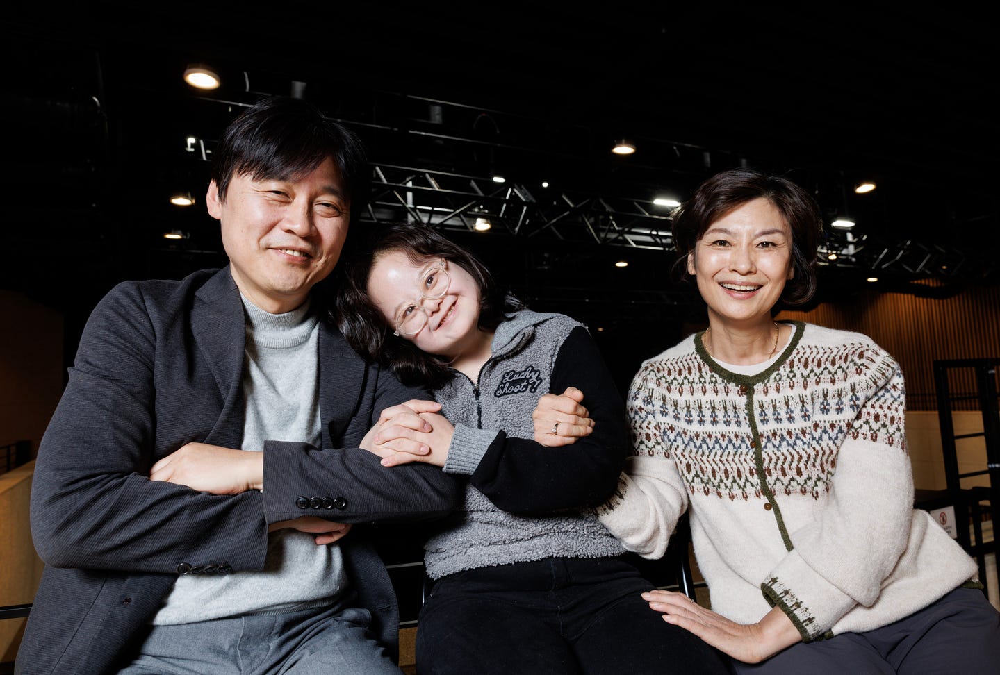 In a photo, a disabled actress poses with her mother and the operating manager of the theater they are in.
