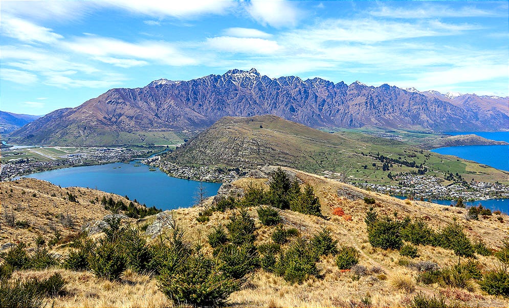 Panoramic view from Queenstown Hill over the Frankton Arm of Lake Wakatipu, showing the airport runway, township, and the Remarkables in the background.