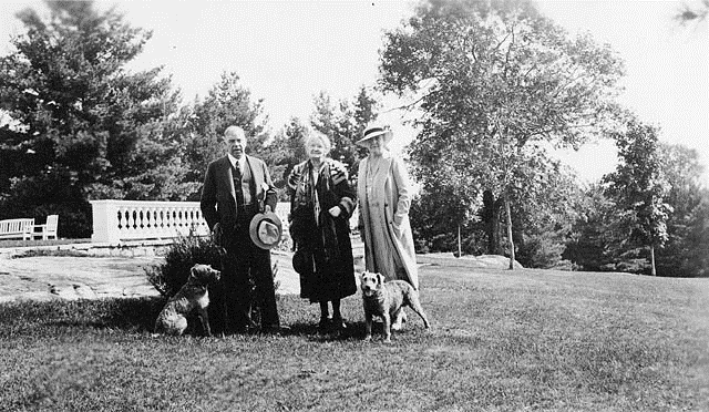 A group of people standing in a park with a dog

Description automatically generated