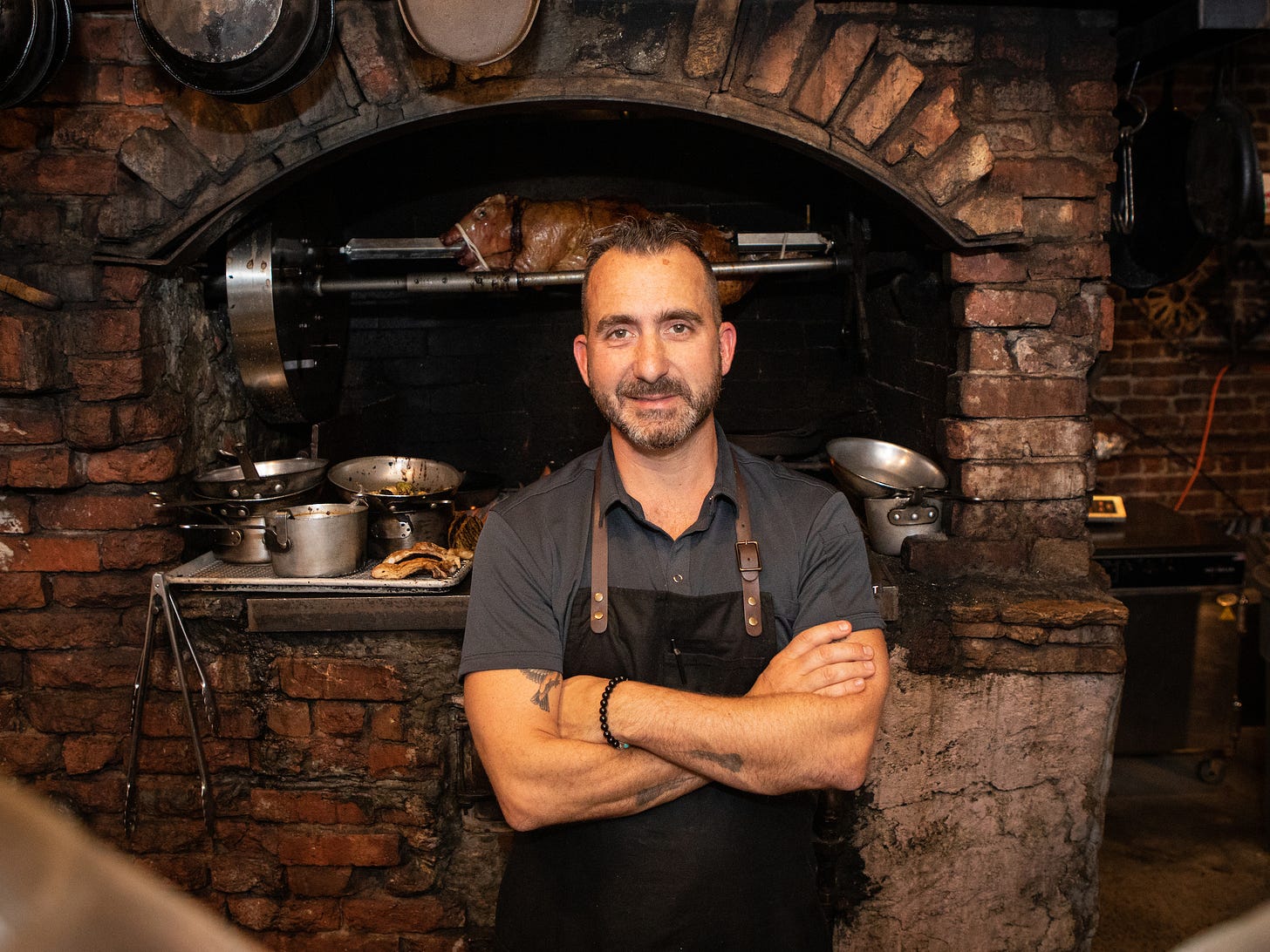 Marc Forgione standing in front of a brick oven