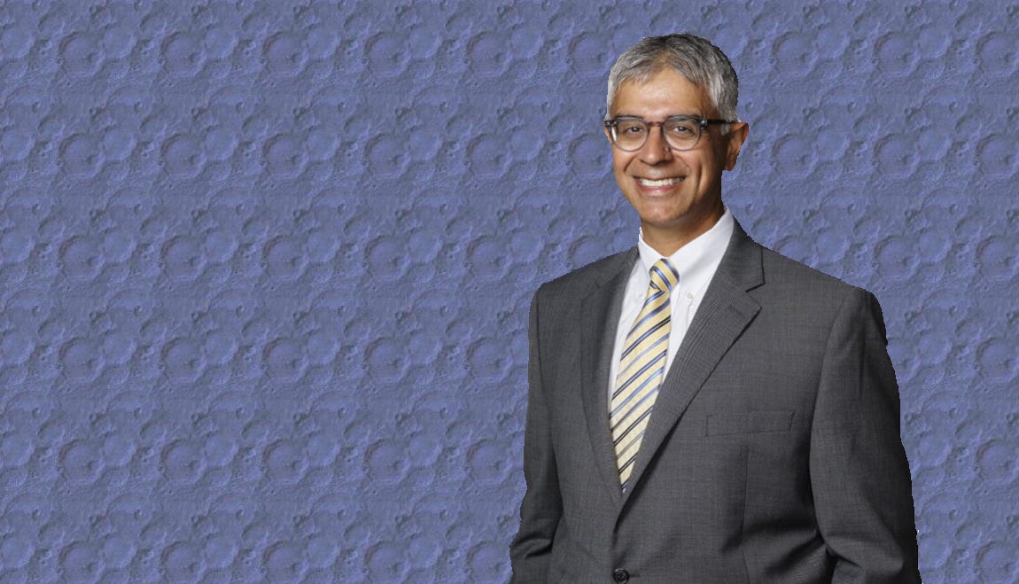 Man wearing dark-gray suit with white shirt and striped tie.