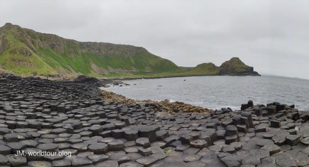 A panoramic picture looking West, Causeway columns in the foreground, green cliffs behind.