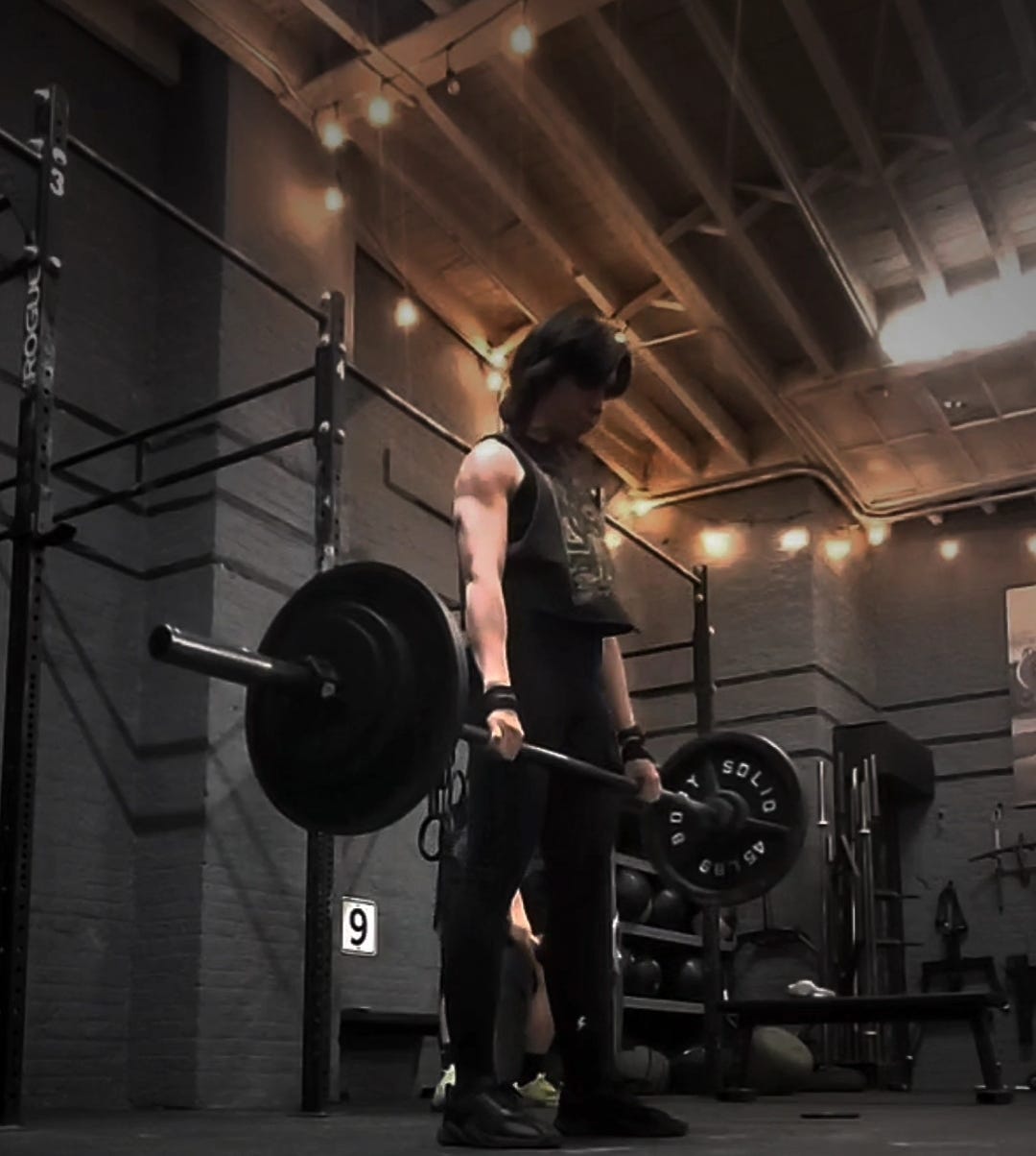 The author is standing up, with a loaded barbell in their hands, having just deadlifted it off the ground. They wear all black and the downlighting of the gym plus the exertion of the effort is making their arms look absolutely diced. Sick. The author is standing up, with a loaded barbell in their hands, having just deadlifted it off the ground. They wear all black and the downlighting of the gym plus the exertion of the effort is making their arms look absolutely diced. Sick.