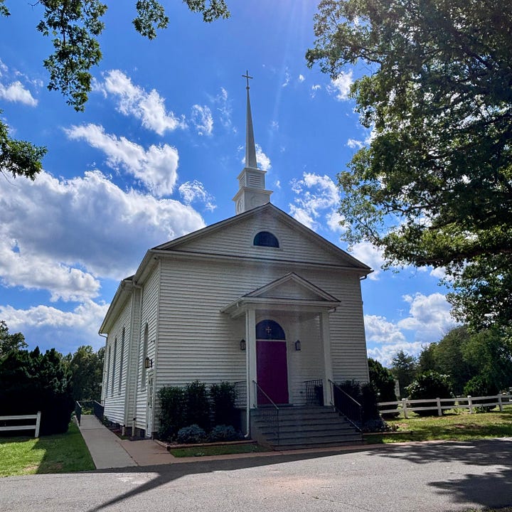 One photo shows a beautiful white wooden church with a red door. The scene is a summer day with a blue sky and puffy white clouds. Another photo shows a sign near the road identifying the name of the church: Walker's Chapel of Madison County. Another photo shows Jeremiah Pent, a man with salt-and-pepper hair and a beard. He is wearing a jacket.
