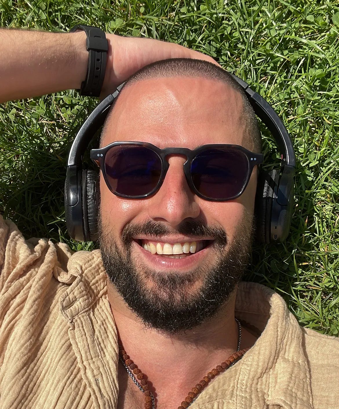 Alessandro sdraiato sull’erba, sorridente e rilassato, simbolo di presenza e gratitudine nel suo percorso da facilitatore mindfulness.