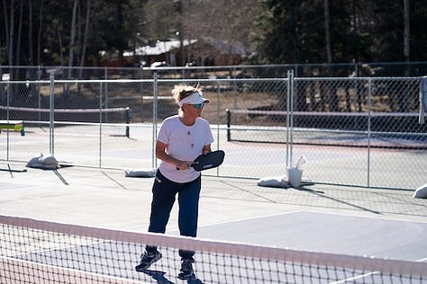 six pickleball courts, players in position, holding their paddles 