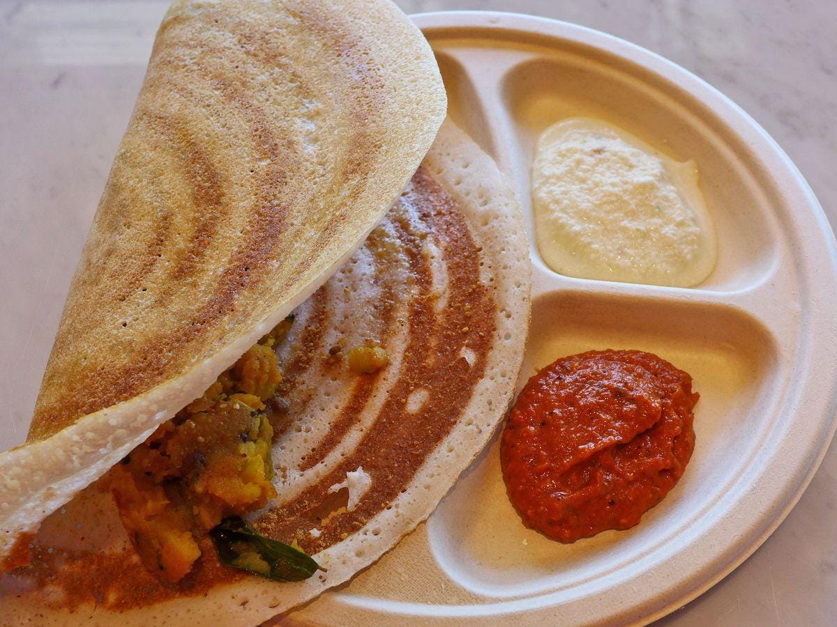 A flatbread folded over a filling, not rolled, and red and white chutneys on the side.