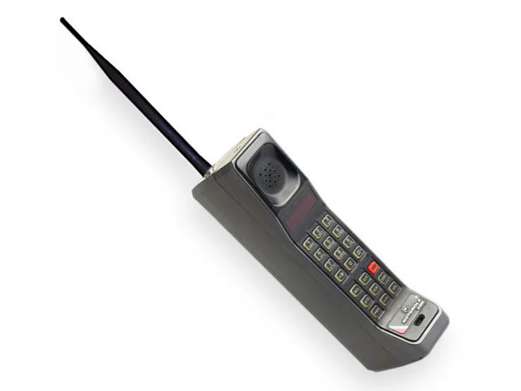 Early 1990s Motorola brick-style mobile phone with long external antenna and numeric keypad.