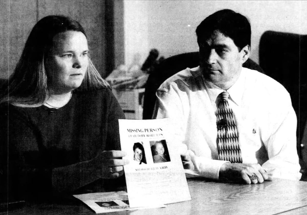 Kara Roberts holds up a missing-person flyer about her sister, Leah Roberts, at a news conference on March 24, 2004.