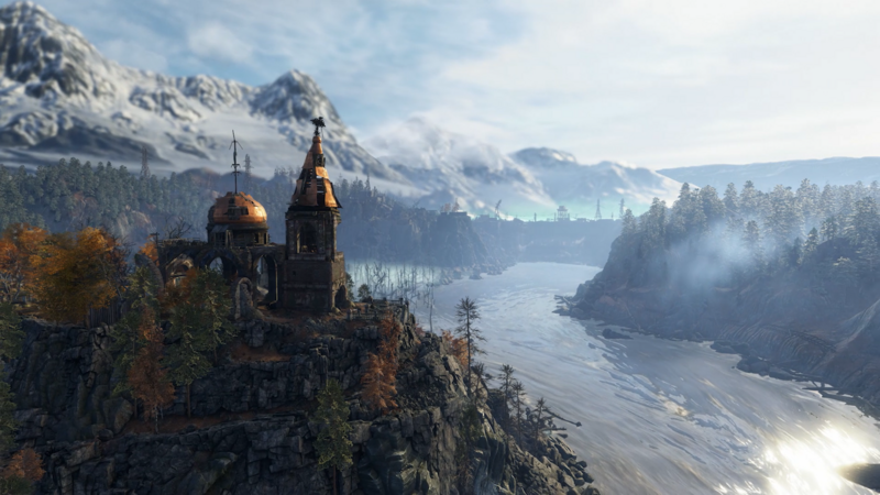 An old church, built by a river, looks out across a mountainous landscape.