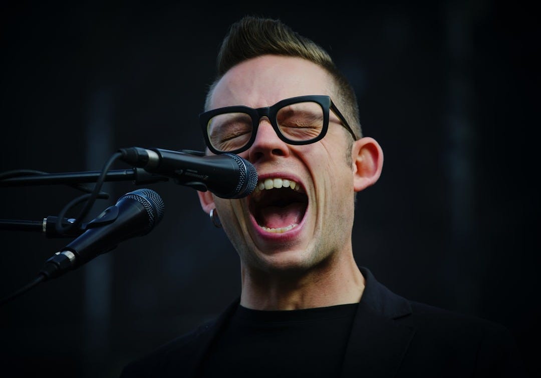 shallow focus photography of man shouting using microphone