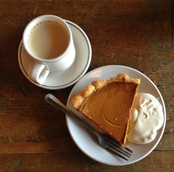 This may contain: a piece of pie on a plate next to a cup of coffee