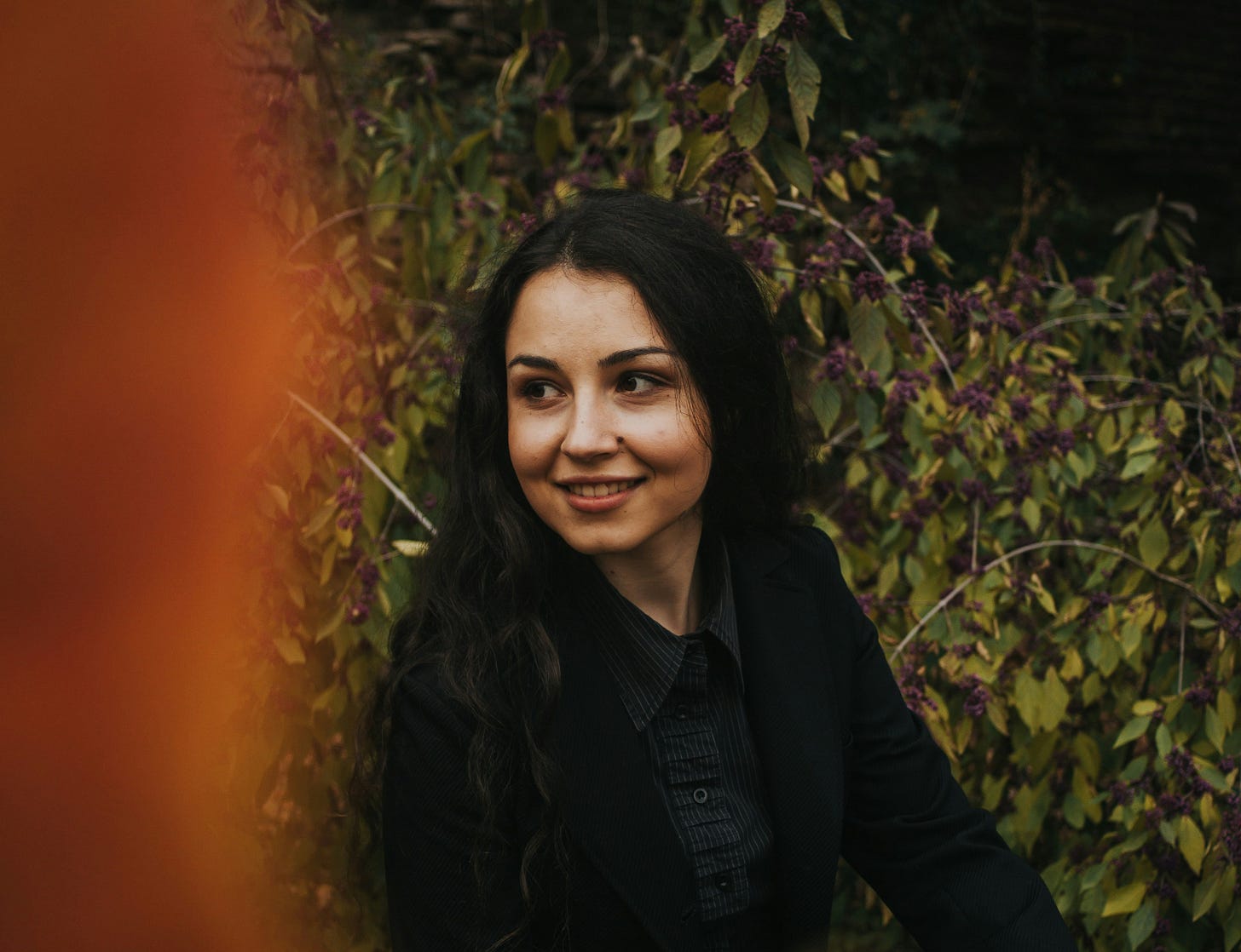 A woman with long black hair smiles and looks off camera