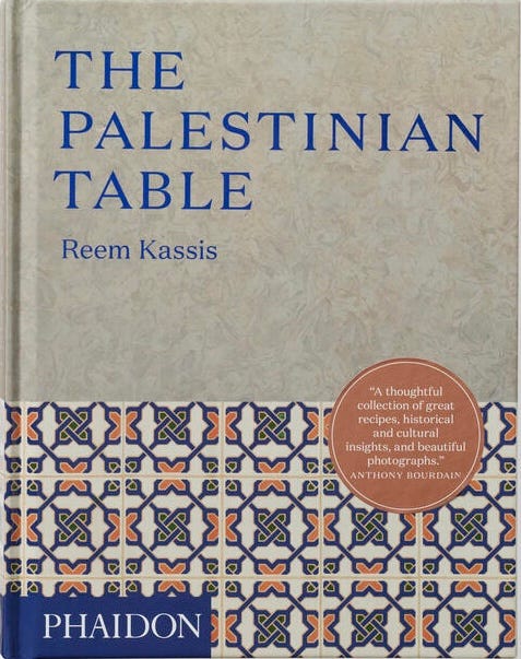Pictured is a marble grey background with a Mosque tile-pattern trim covering a third of the page at the bottom. Anthony Bourdain is quoted at the bottom of the book cover as “A thoughtful collection of great recipes, historical and cultural insights, and beautiful photographs.” The title “The Palestinian Table” is written in a bright cobalt-blue font.