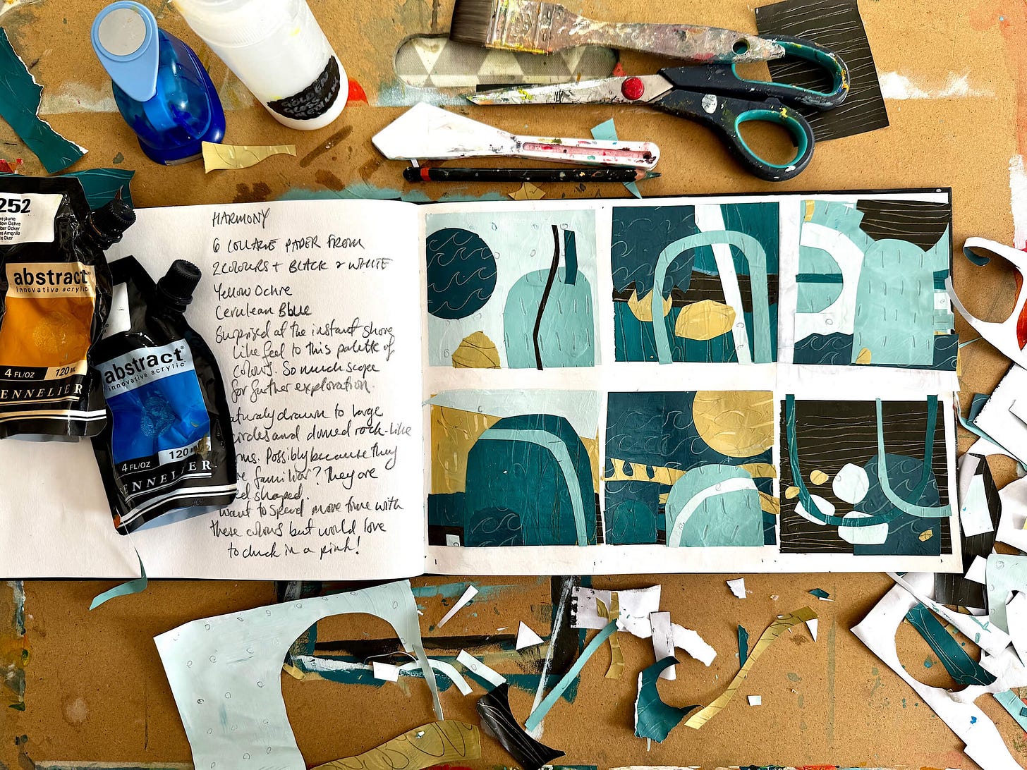 Art table with an A4 sketchbook, acrylic paint pouches, scissors, pencil, glue, paintbrush, palette knife and hole punch and a series of six mini collages made with hand made collage paper in shades of duck egg blue, teal, sand and bark