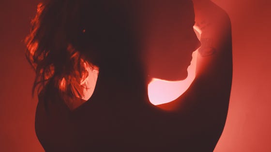 Silhouette in pomegranate red of a woman looking at you over her shoulder.