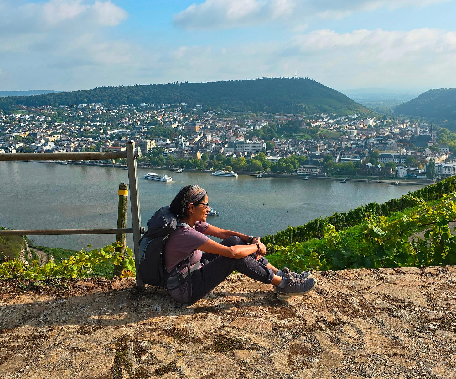 Author Anu Kay sitting on top of a mountain with a river flowing by— symbolising calm, reflection, and mental stillness.
