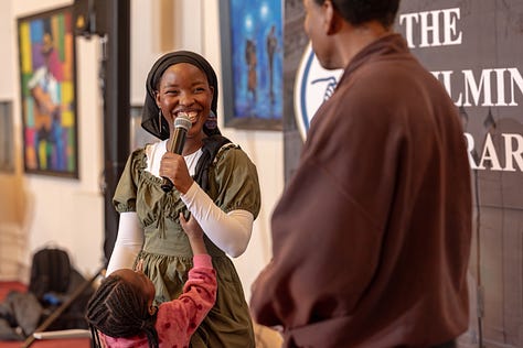 Teledalase singing and playing her hand drum with her child at Delaware Music Network Open Mic.
