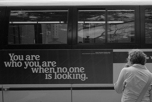 This may contain: a woman standing in front of a bus talking on her cell phone with the words you are who you are when no one is looking This may contain: a woman standing in front of a bus talking on her cell phone with the words you are who you are when no one is looking